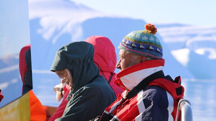 Mennesker i solen ombord på gul båd på isfjorden