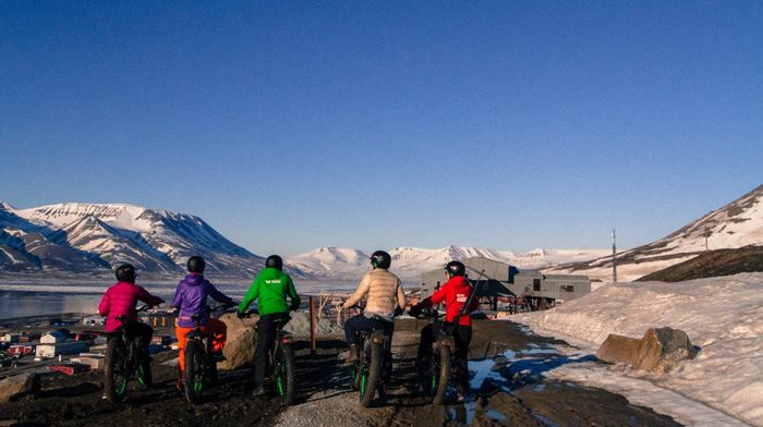 fem mennesker på cykleudflugt nyder udsigt over sneklædte bjerge