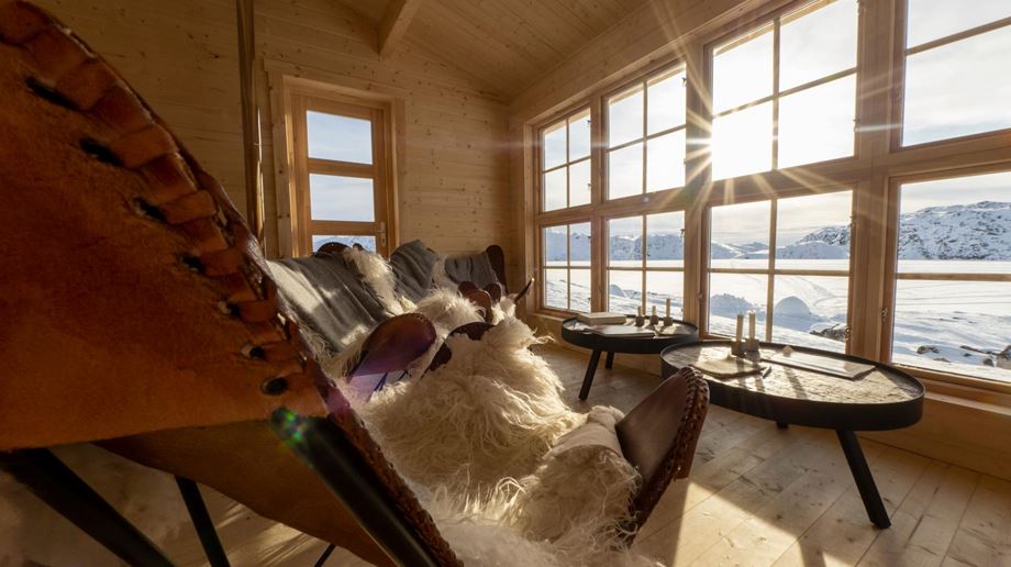 Hyggeligt hjørne i hytte med skindbeklædte stole og udsigt over igloerne