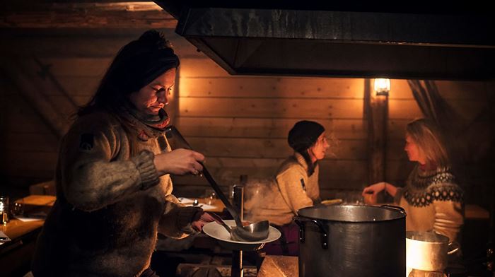 Camp Barentz: i dunkel belysning serverer kvinde suppe for 2 gæster