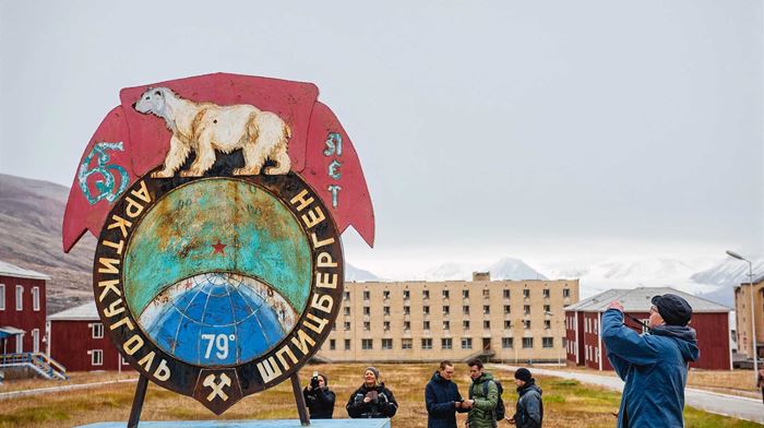 Turister tager billeder af skilt med isbjørn