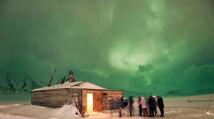 Camp Barentz: en flok mennesker beundrer den grønne nordlys himmel