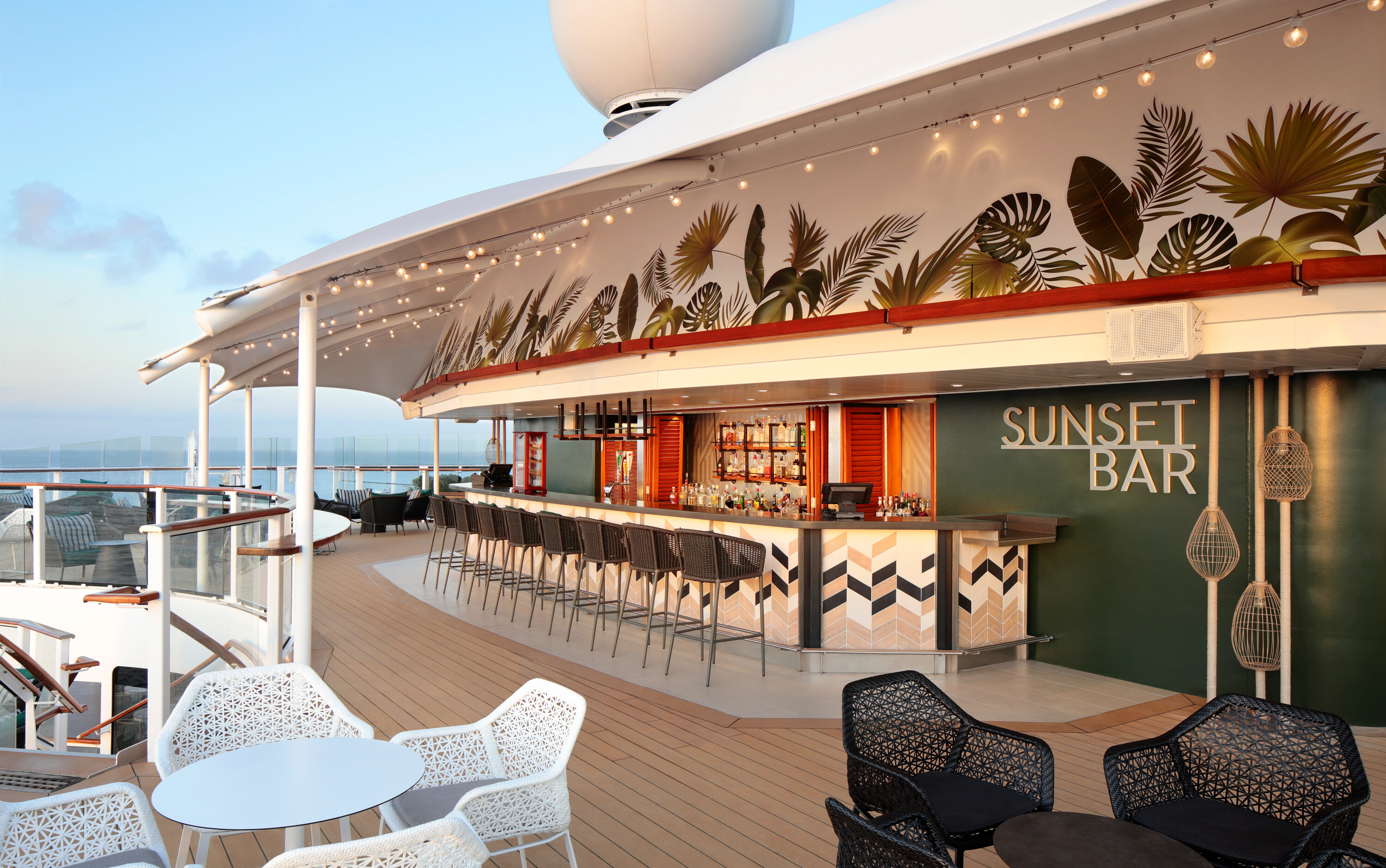 Sunset Bar på Celebrity cruise skibets øverste dæk med tropisk palmeblade-dekoration, udendørs barstemning og havudsigt
