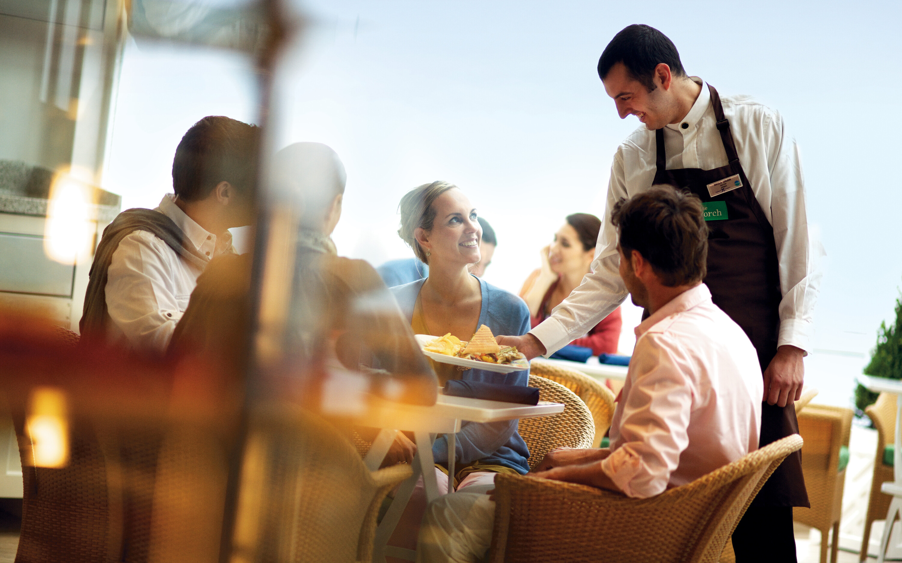 Gæster nyder gourmetmiddag på The Porch specialitetsrestaurant ombord på Celebrity skibet med professionel servering i elegant atmosfære