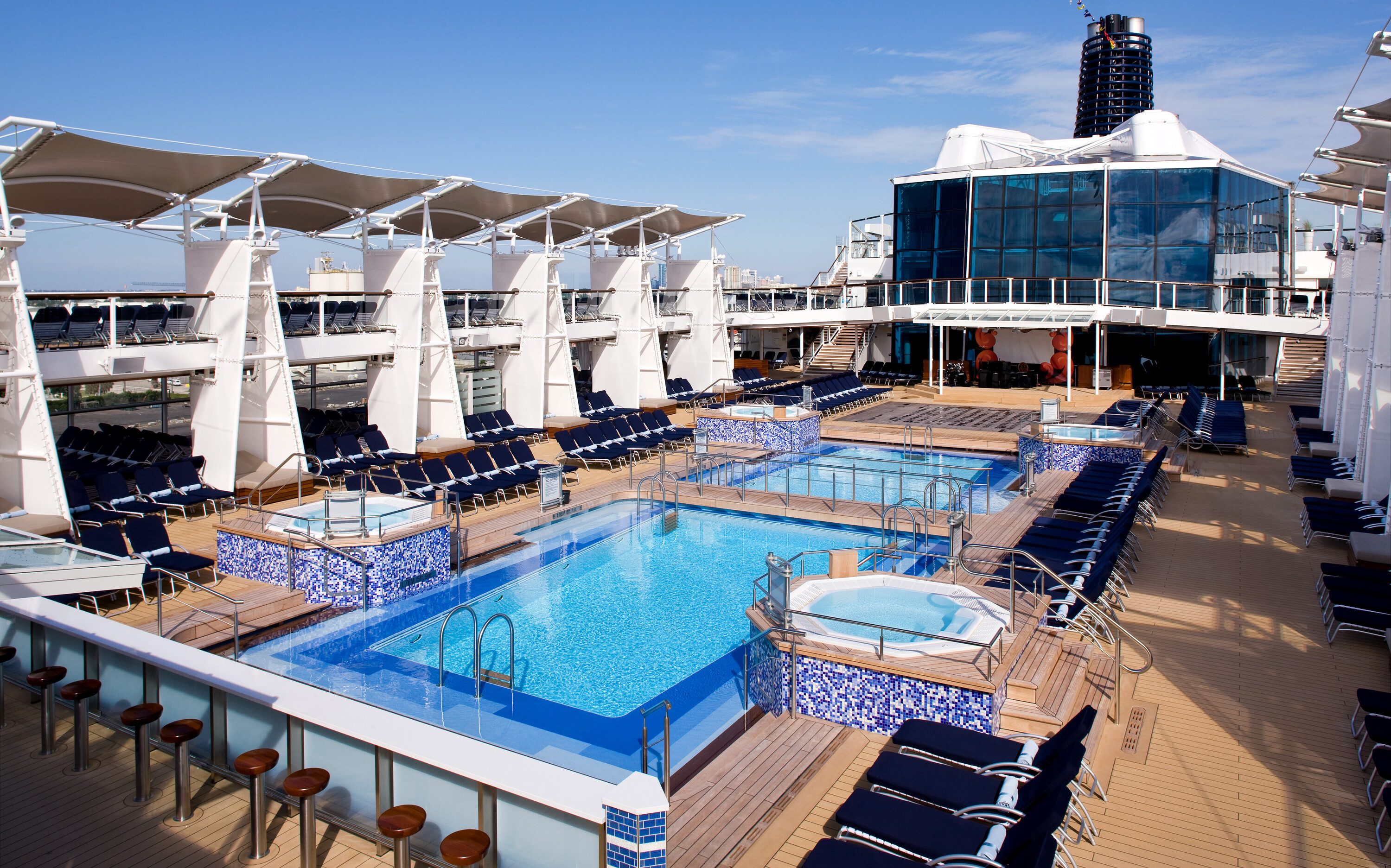 Celebrity Cruises pool-dæk med infinity pool, blå mosaikfliser, hvide markiser og solstole på luksus cruiseskib