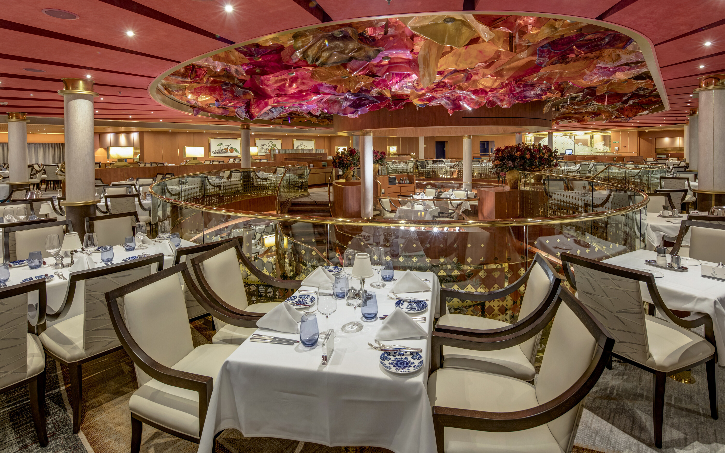 Elegant hovedrestaurant på MS Westerdam med hvide duge, dækkede borde og kunstnerisk loftsdekoration
