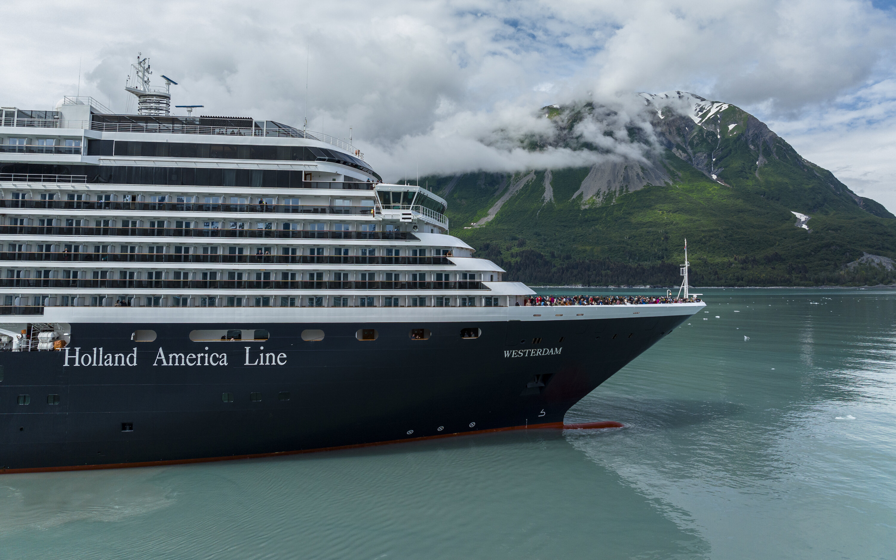 Krydstogtskibet MS Westerdam sejler gennem Yakutat Bay med grønne bjerge og skyer i baggrunden