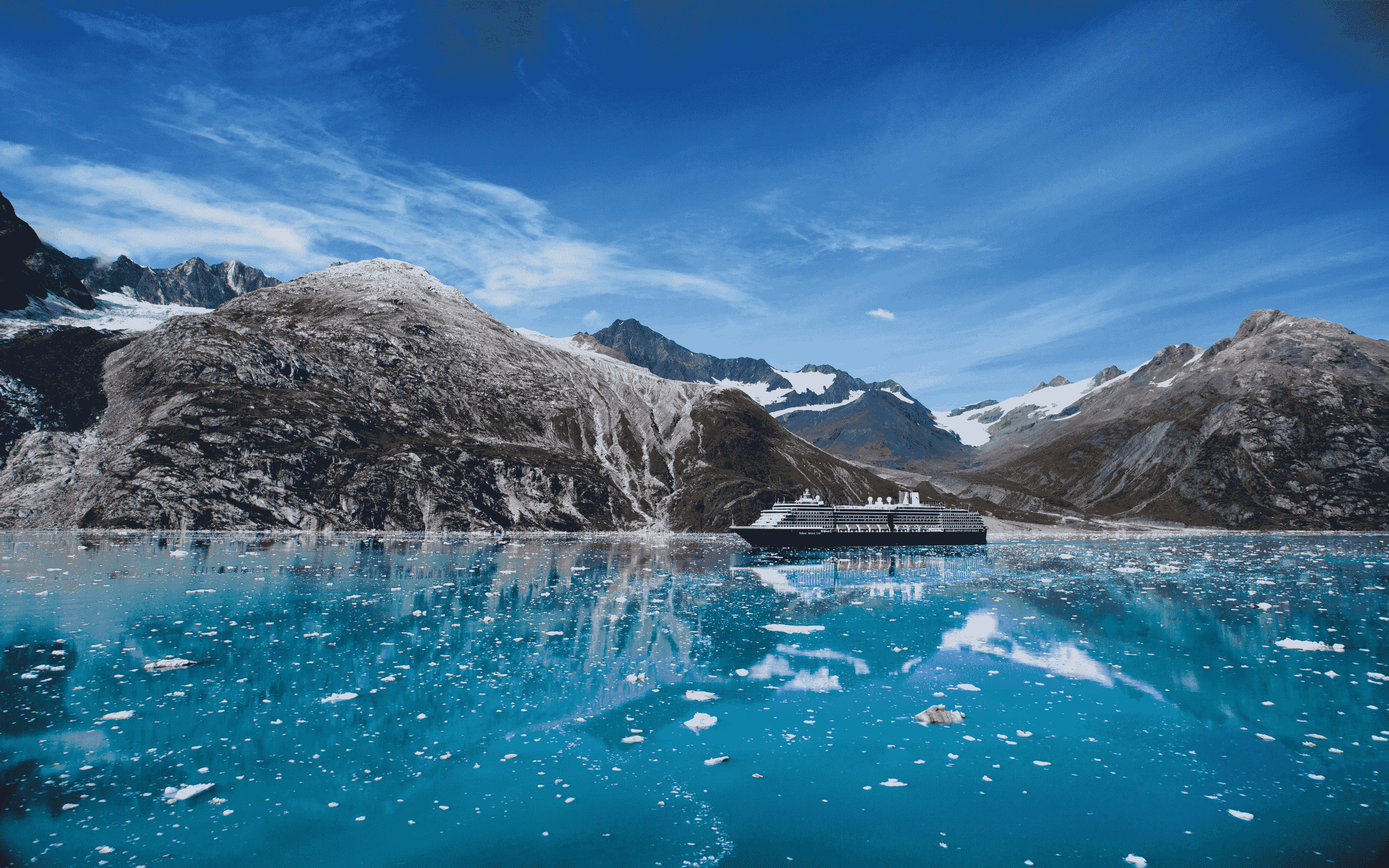Holland America Line krydstogtskib sejler gennem Glacier Bay med isbjerge og bjerge, Alaska