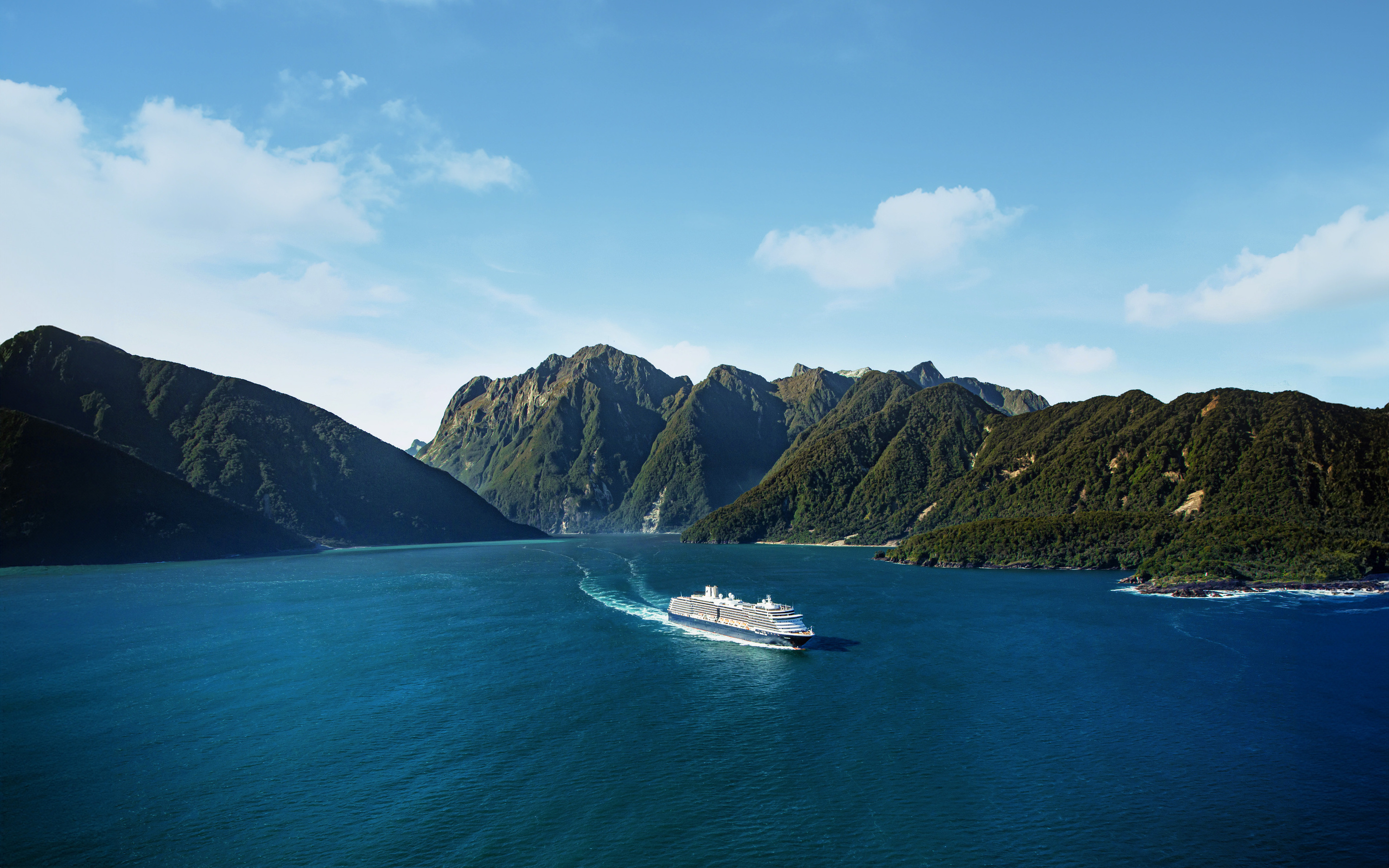 Holland America Line krydstogtskib sejler gennem Milford Sound med dramatisk bjerglandskab og vandfald