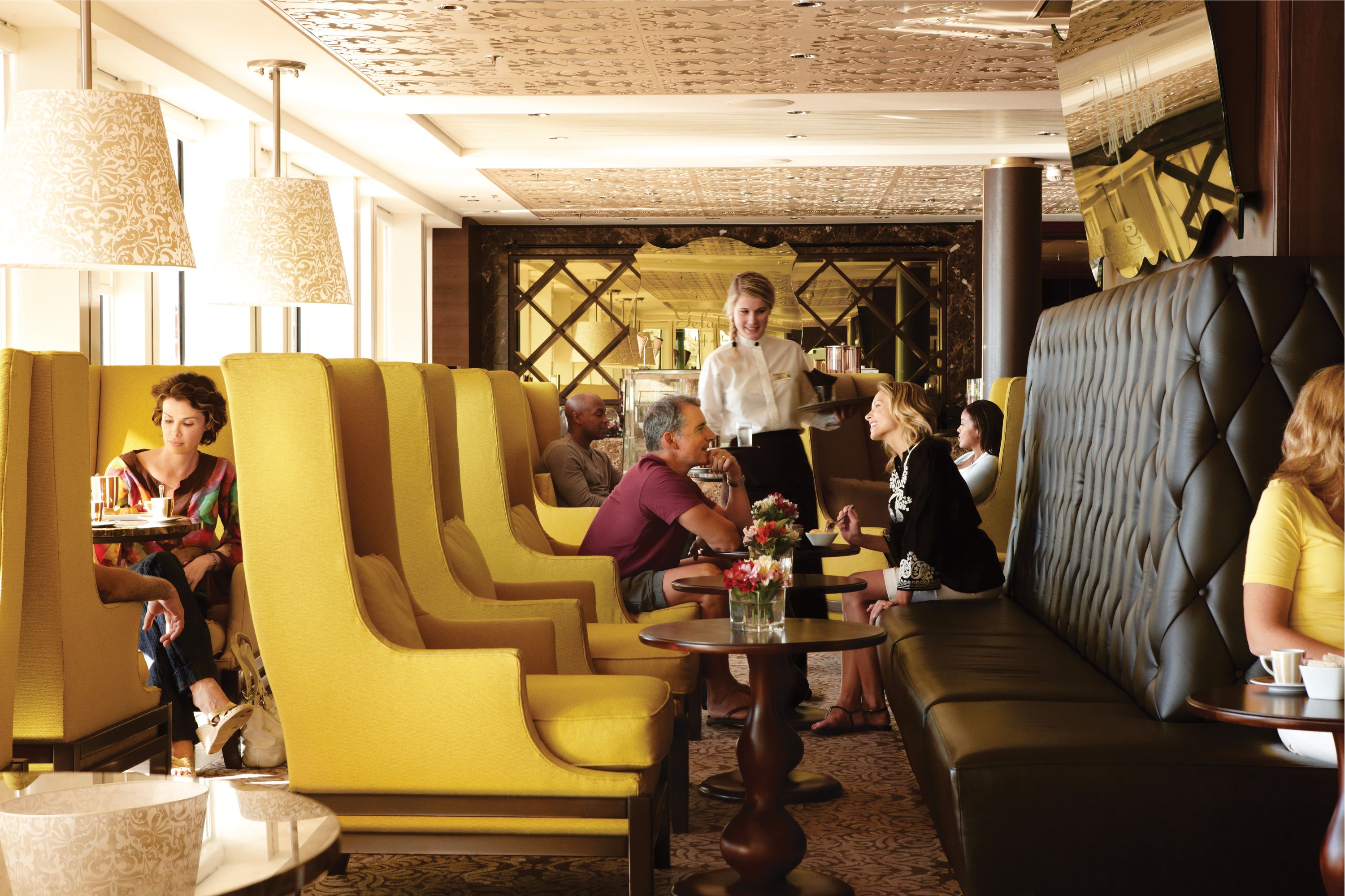 Celebrity Equinox Cafe Baccio - En elegant cafe med karakteristiske gule loungestole og sofistikeret indretning med integreret kunst i loftet