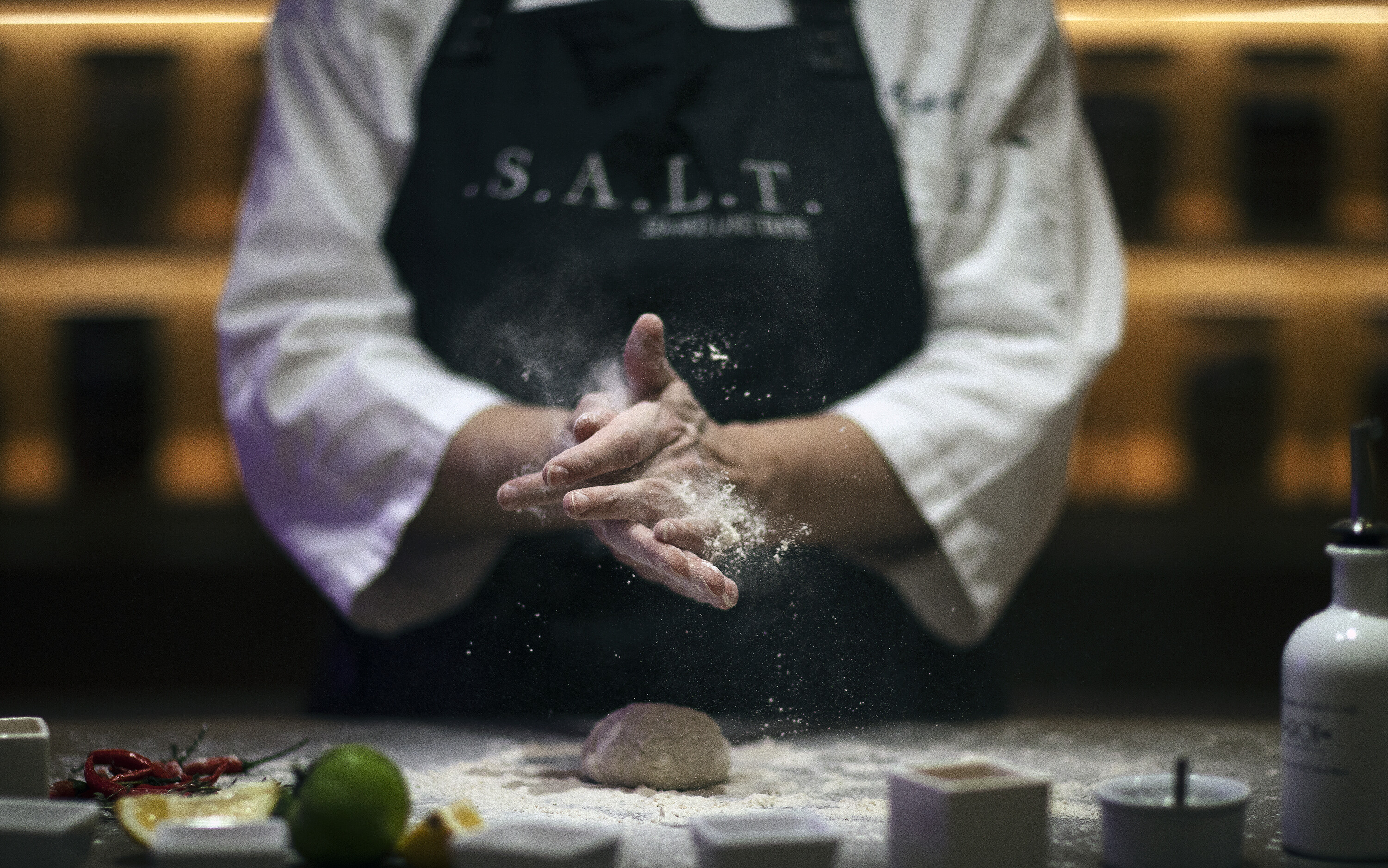 Kok i S.A.L.T.-køkkenet former dej og drysser mel under kulinarisk oplevelse ombord