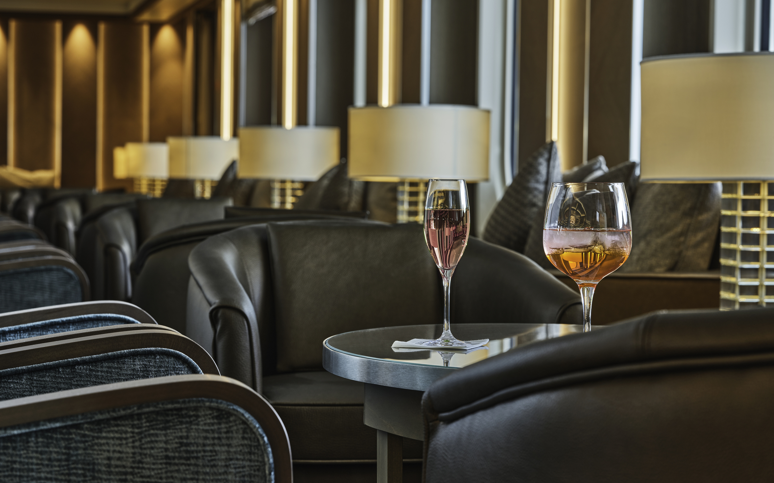 To farverige cocktails på bord mellem lænestole i eksklusiv bar-lounge ombord på Silversea