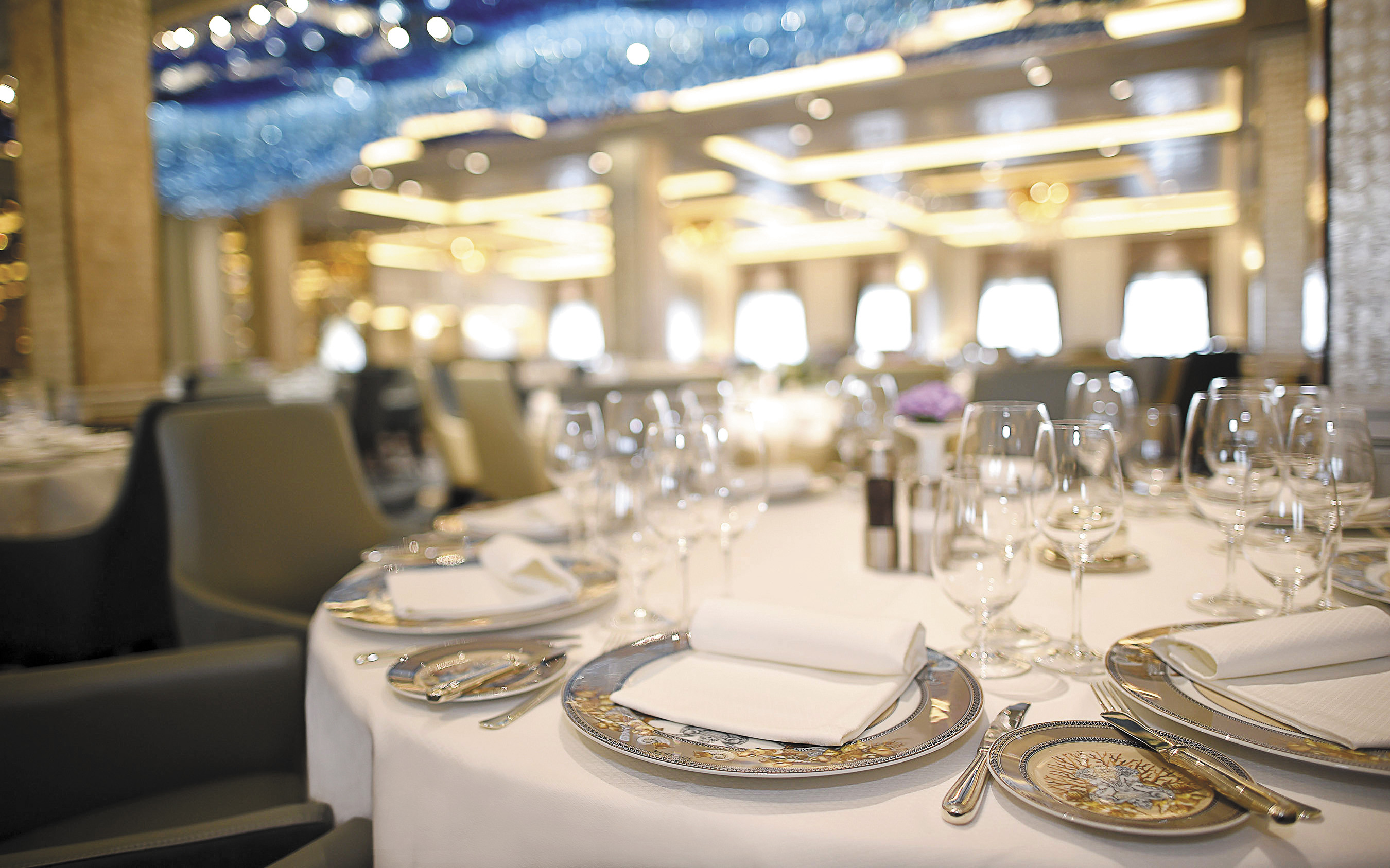 Hovedrestauranten Compass Rose med dækkede borde og krystalglas på Seven Seas Explorer
