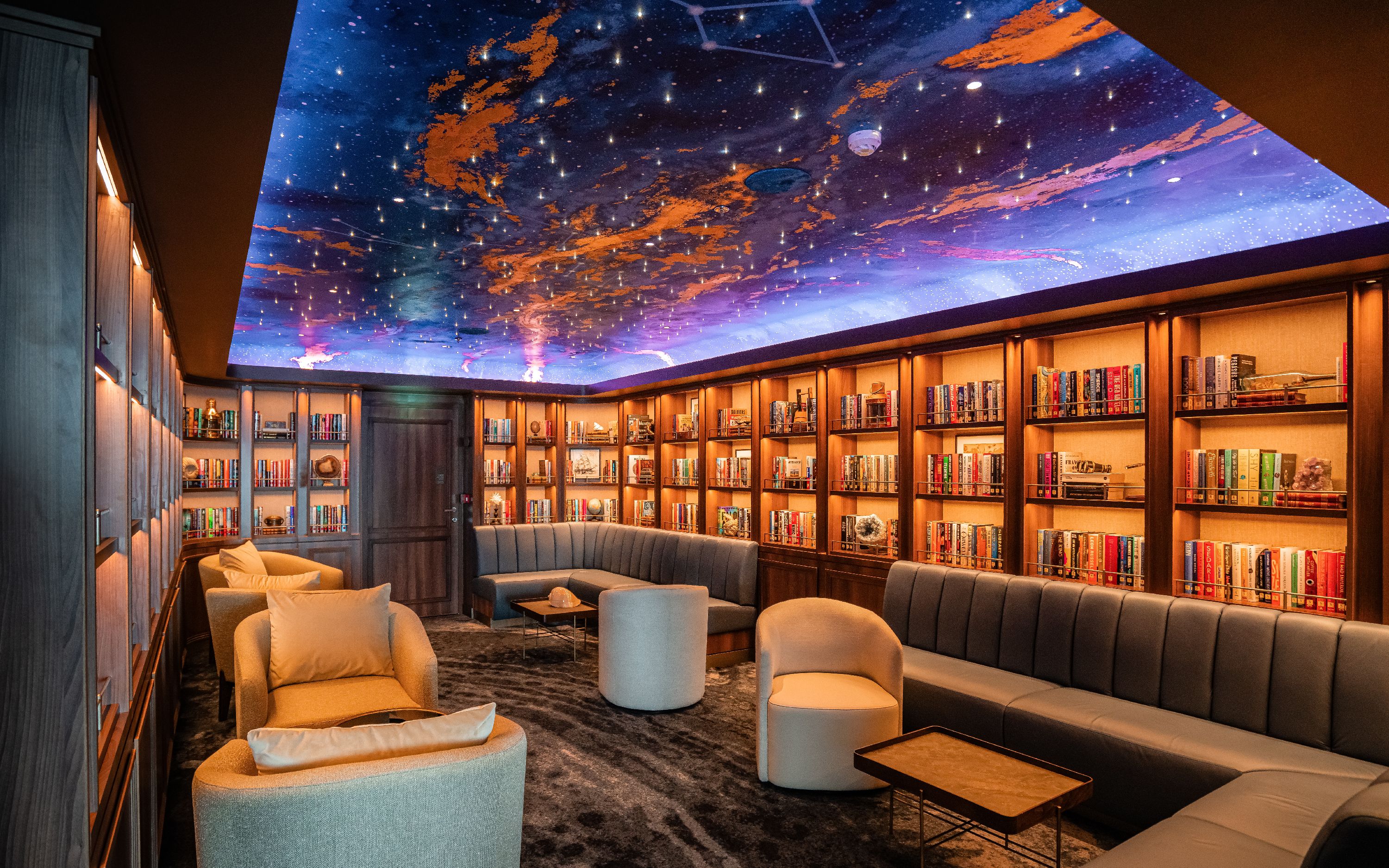Stemningsfuldt bibliotek ombord på Silver Nova med bogreoler og loungemøbler