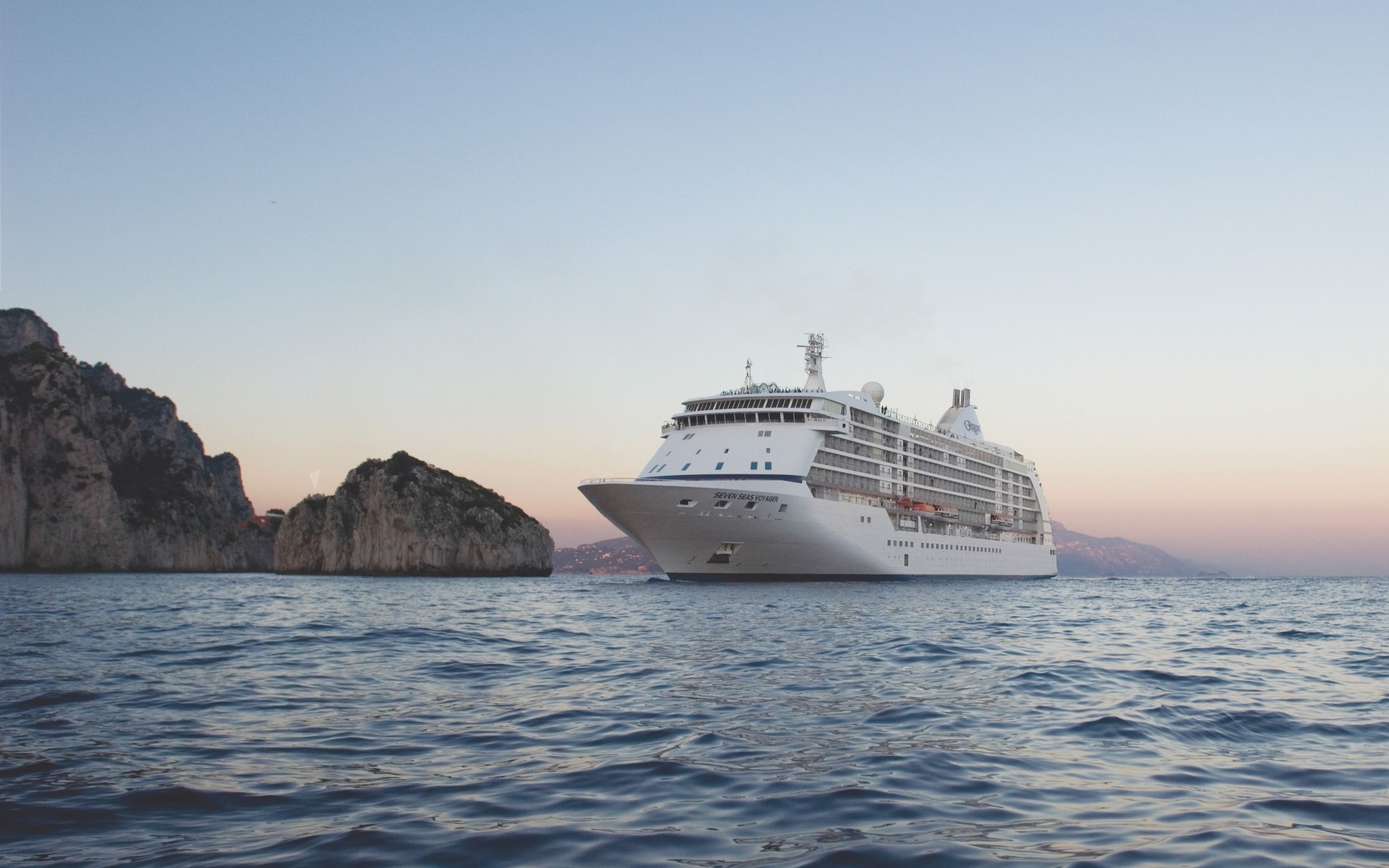 Krydstogtskibet Seven Seas Voyager sejler ved Capri blandt klipper i solnedgang