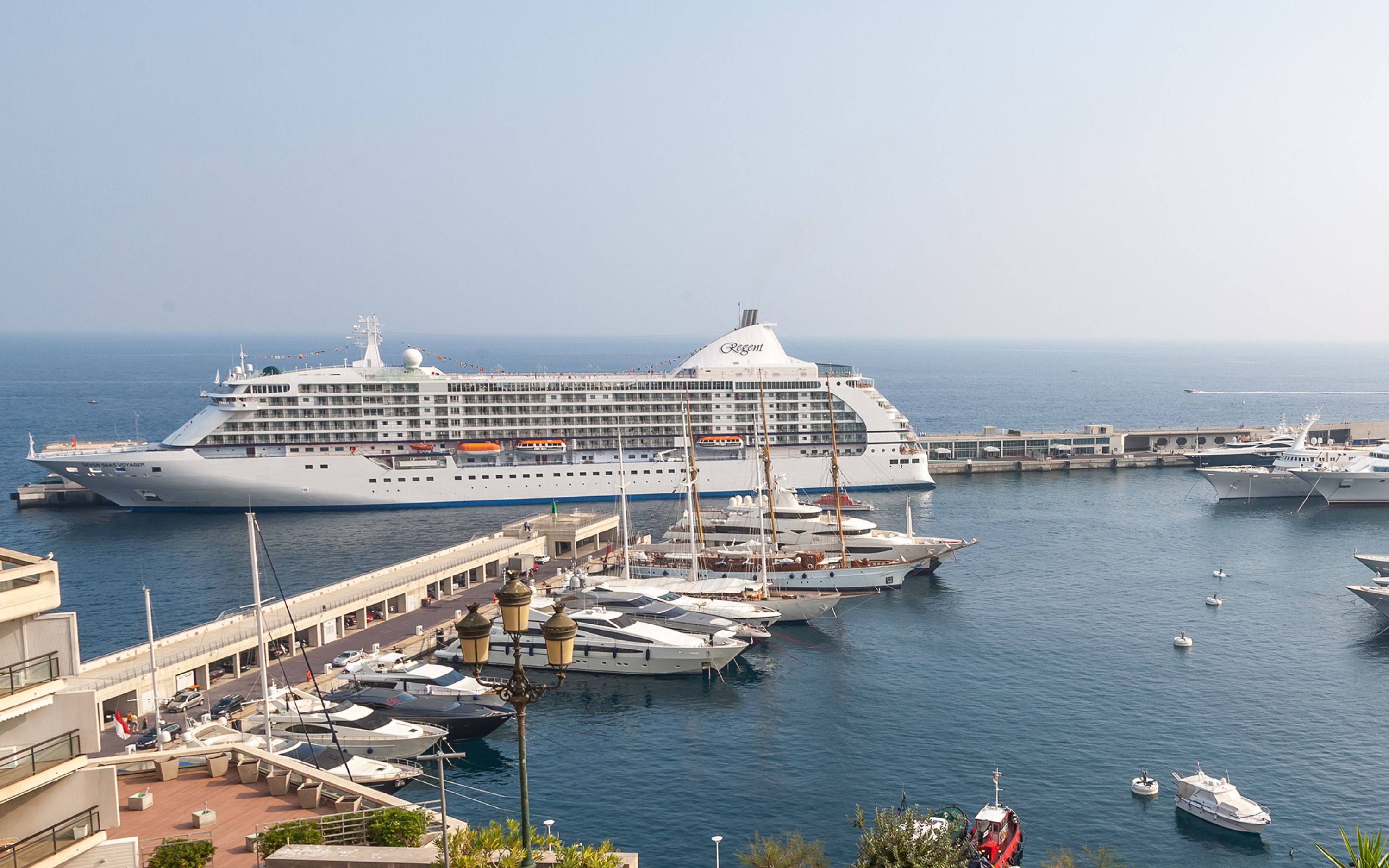 Seven Seas Voyager ved kaj i Monaco omgivet af lystbåde og havnepromenade