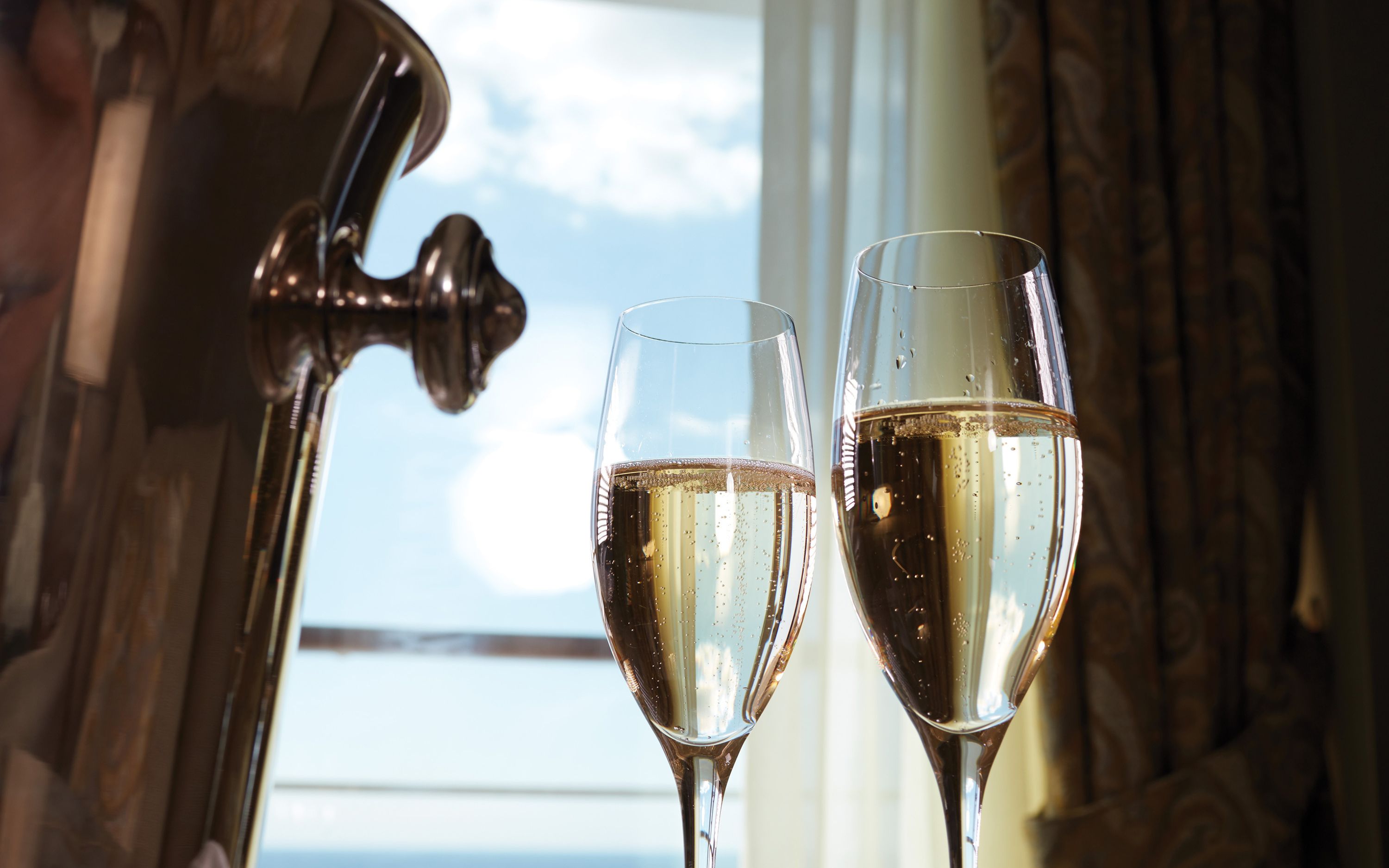 To glas boblende champagne ved vinduet med havudsigt på Seven Seas Voyager